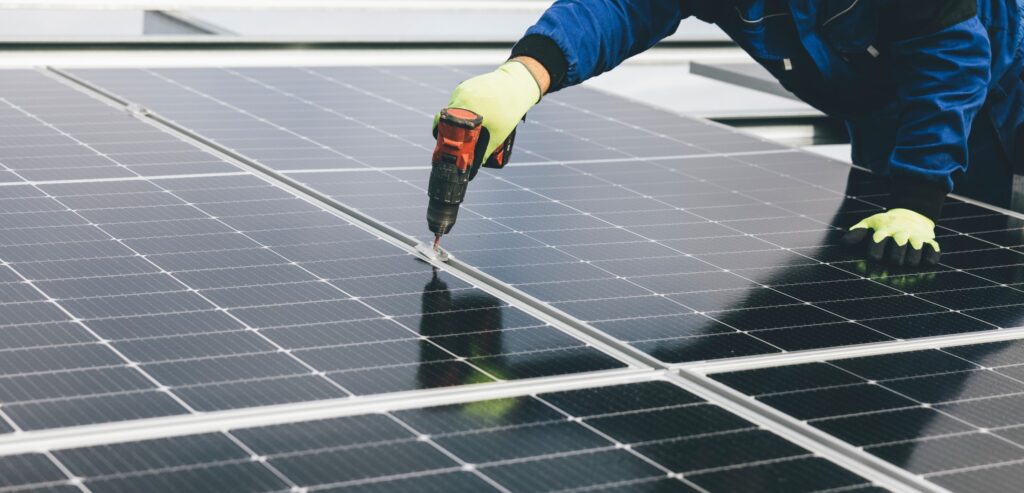 Solar technician installing solar panels on roof